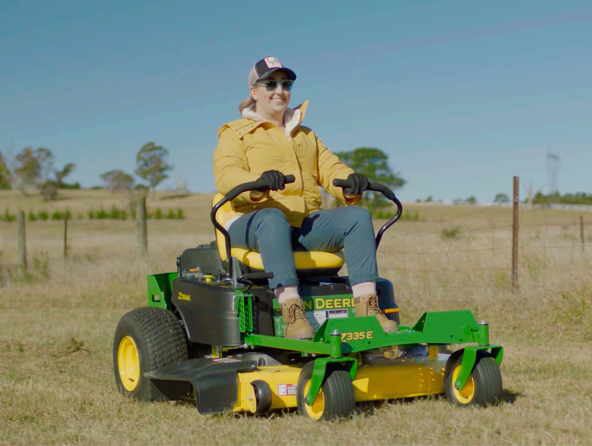 Woman riding a John Deere ride-on mower on her backyard golf course.