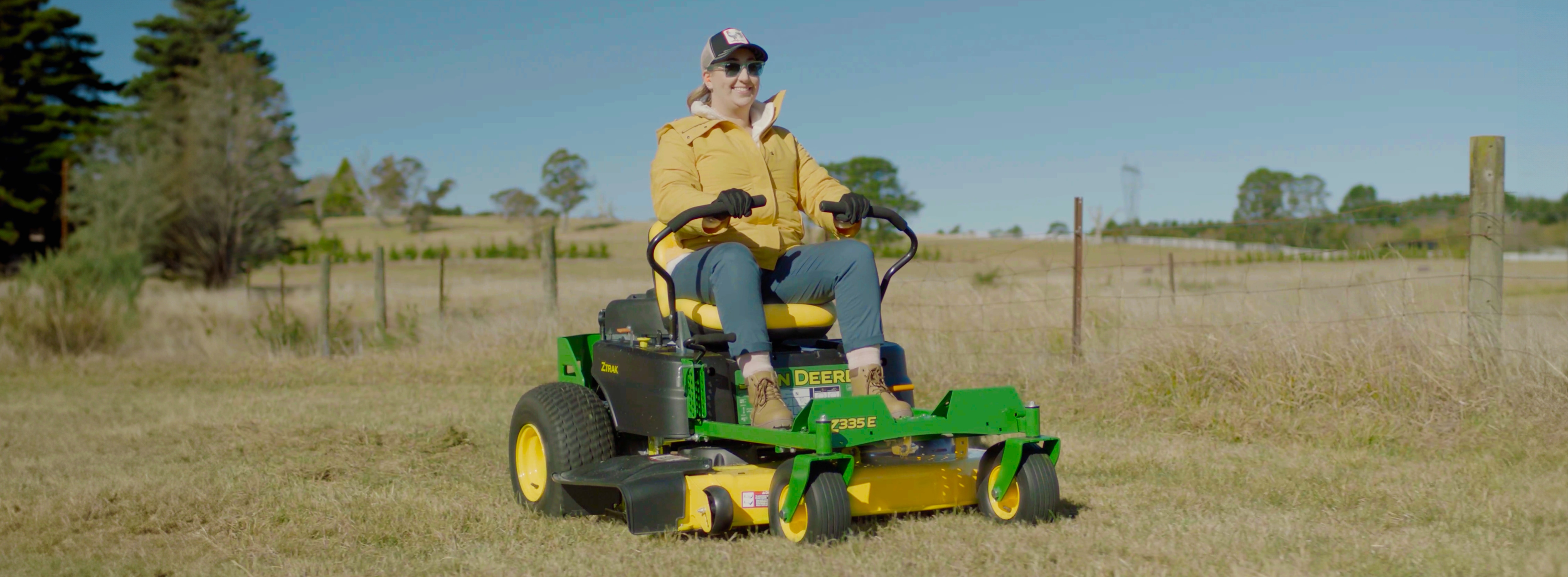 Woman riding a John Deere ride-on mower on her backyard golf course.