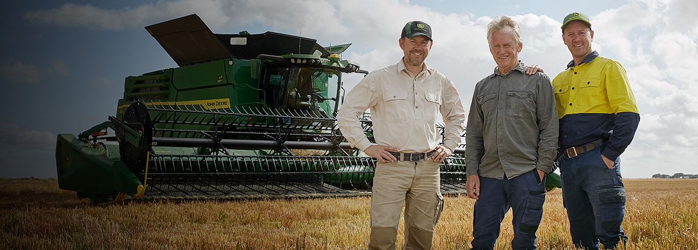 Three Rethus family members stand together in front of their John Deere X9 Harvester