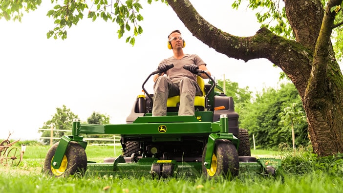 Operator on a John Deere mower precisely landscaping huge grounds.