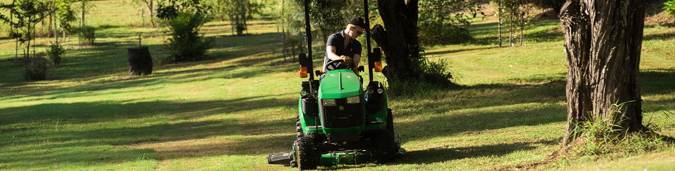 Man mowing grounds using John Deere's landscaping equipment.