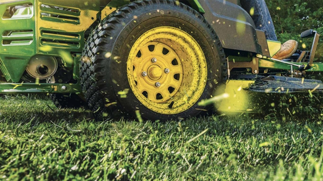 woman gardening with a Deere compact tractor in the background