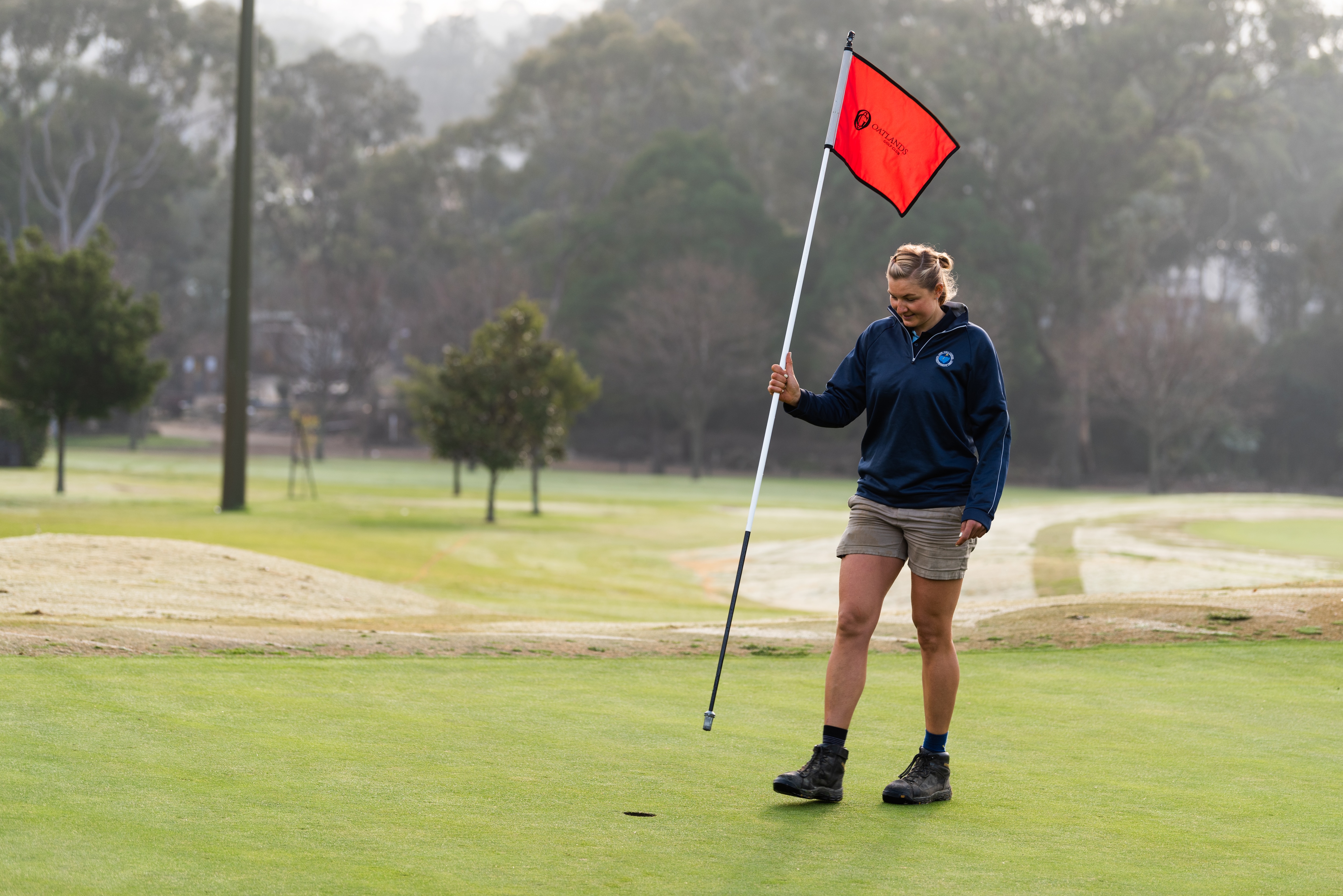 Martyna Synak placing in the flag on the putting green 