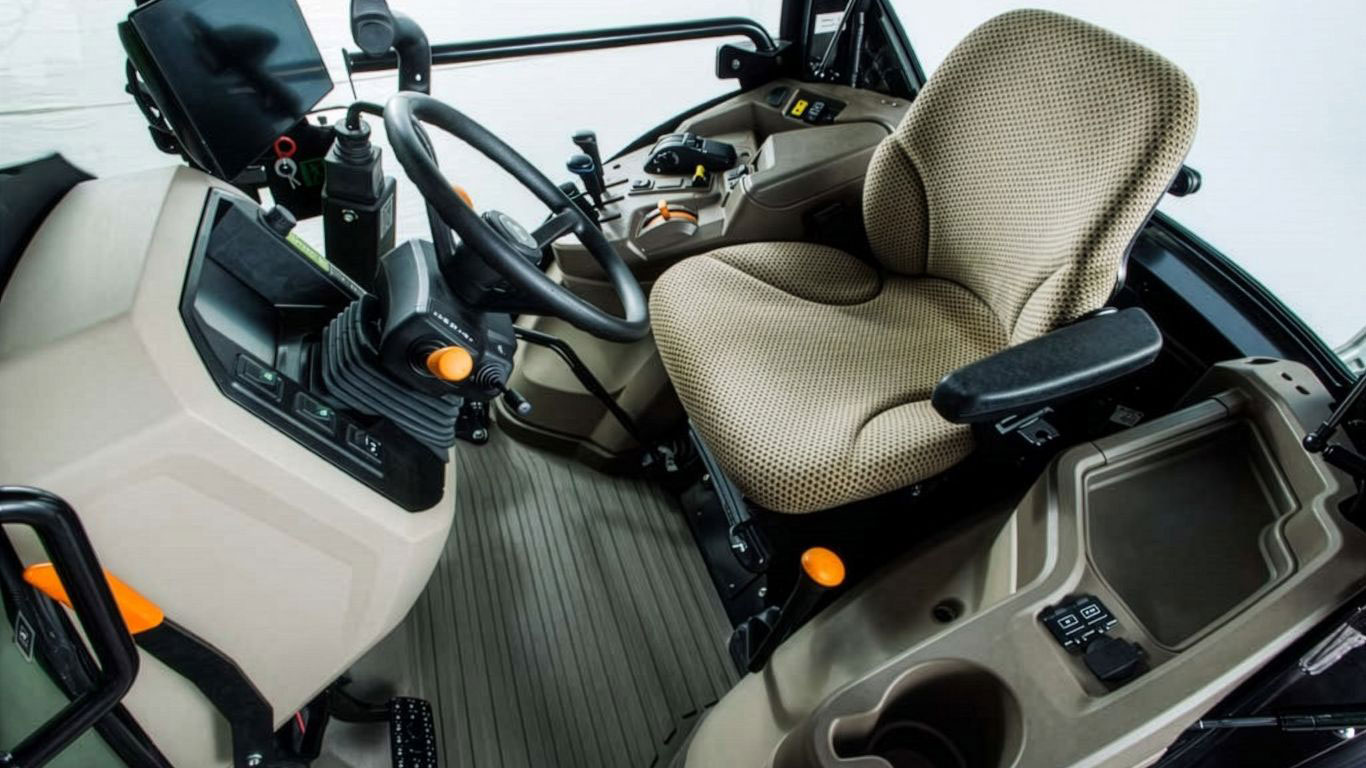 Close-up of tractor's interior, featuring a plush, ergonomic seat, controls, and a dashboard display.