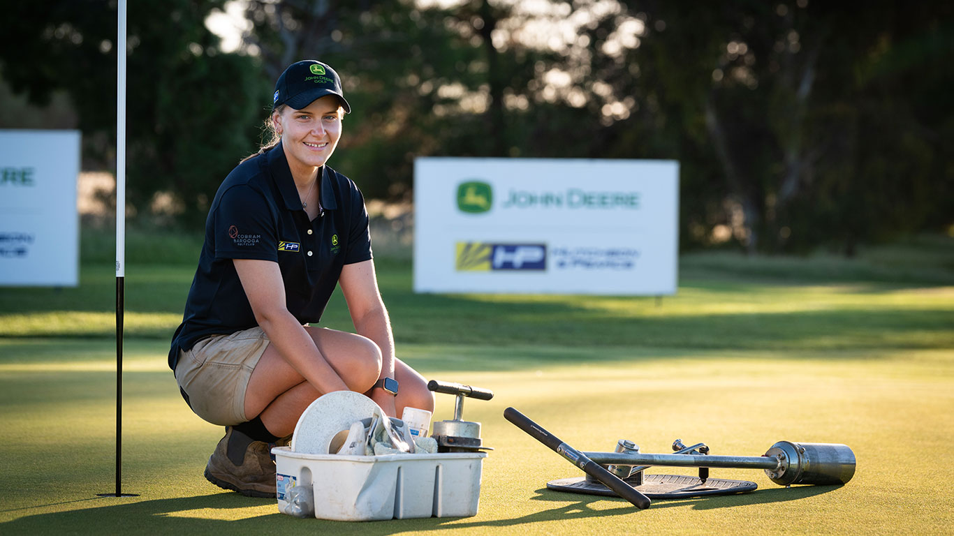 Female Volunteer changing hole on the turf