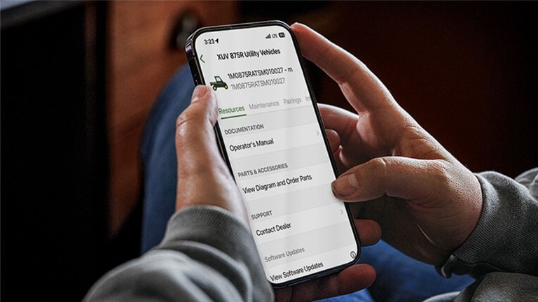 Close-up image of hands holding a cell phone looking at machine information.