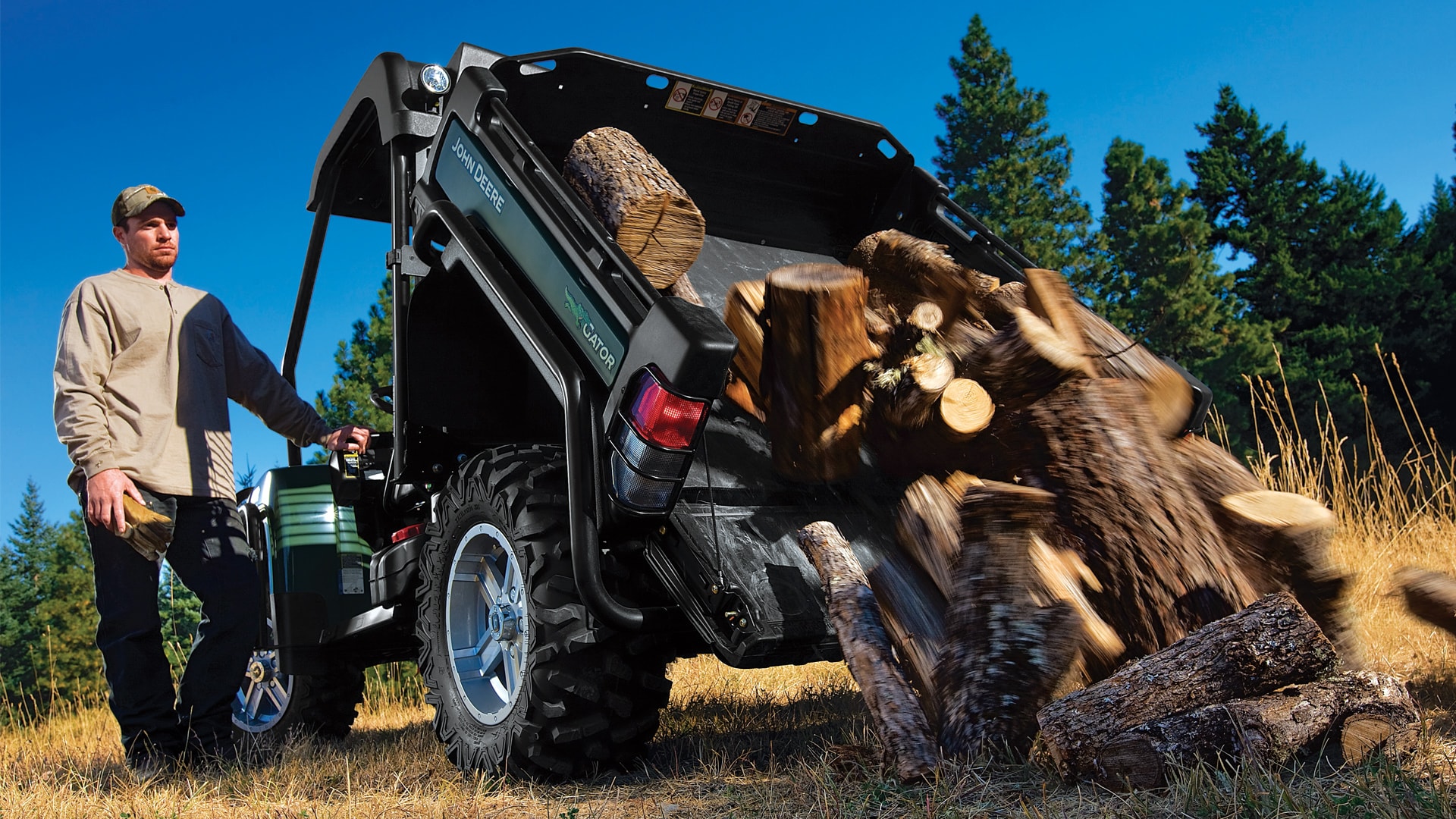 A man dumping wood out of the back of his Gator