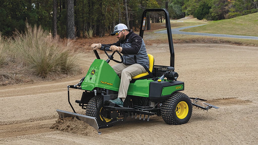 Man raking sand on a golf course with a TruFinish™ 1220 Utility Rake