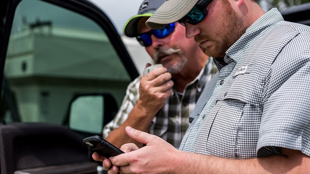 two farmers checking out John&nbsp;Deere Operations Center&trade; on a mobile phone