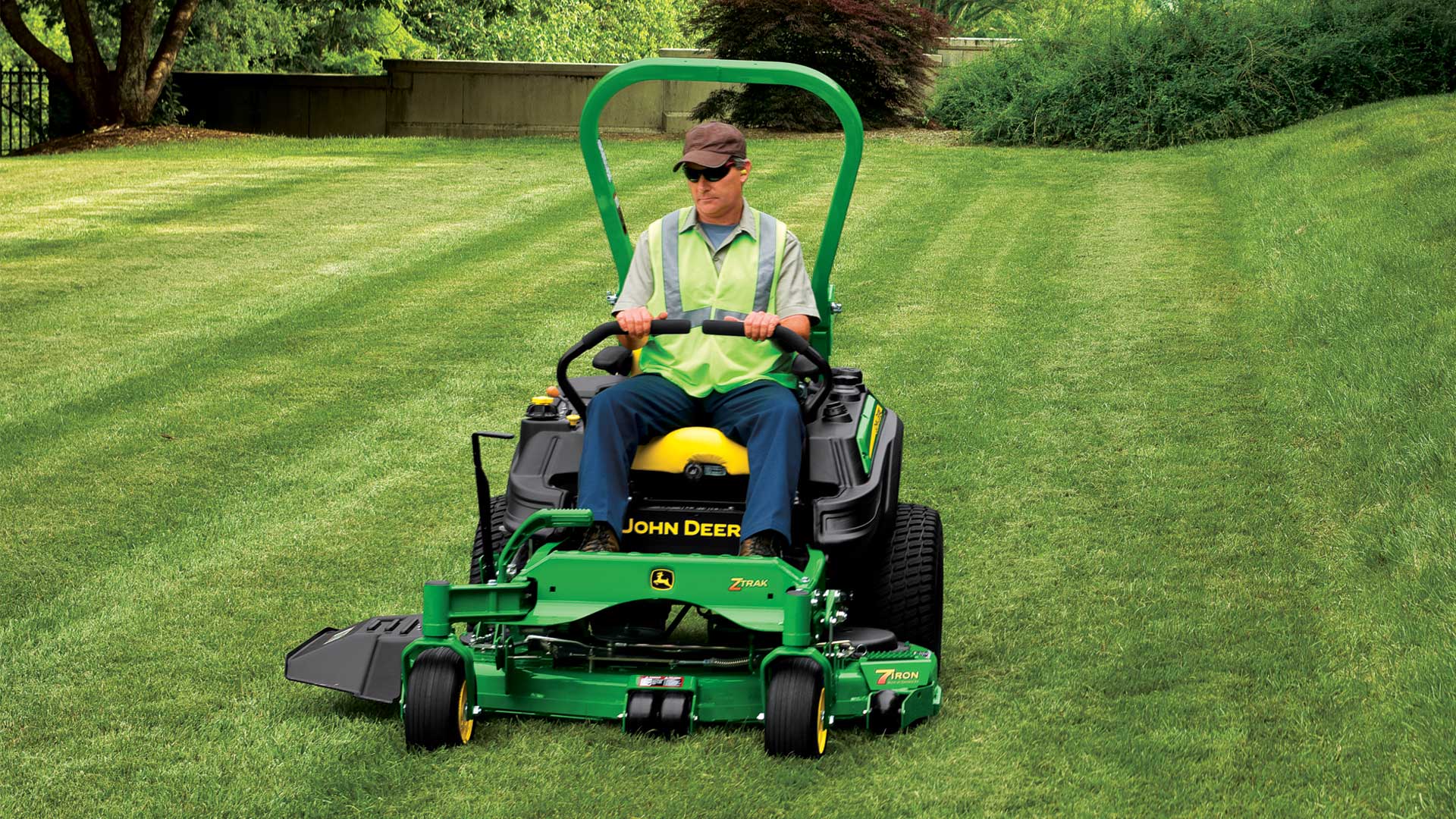 A man riding a John Deere AU zero turn mower for commercial and industry use.