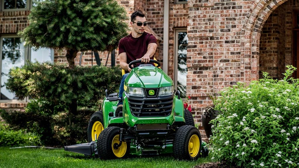 man on a heavy duty ride on mower x590 lawn tractor in yard