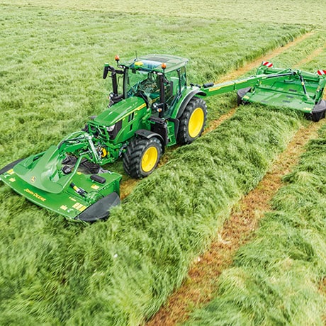 tractor mows tall grass in a field.
