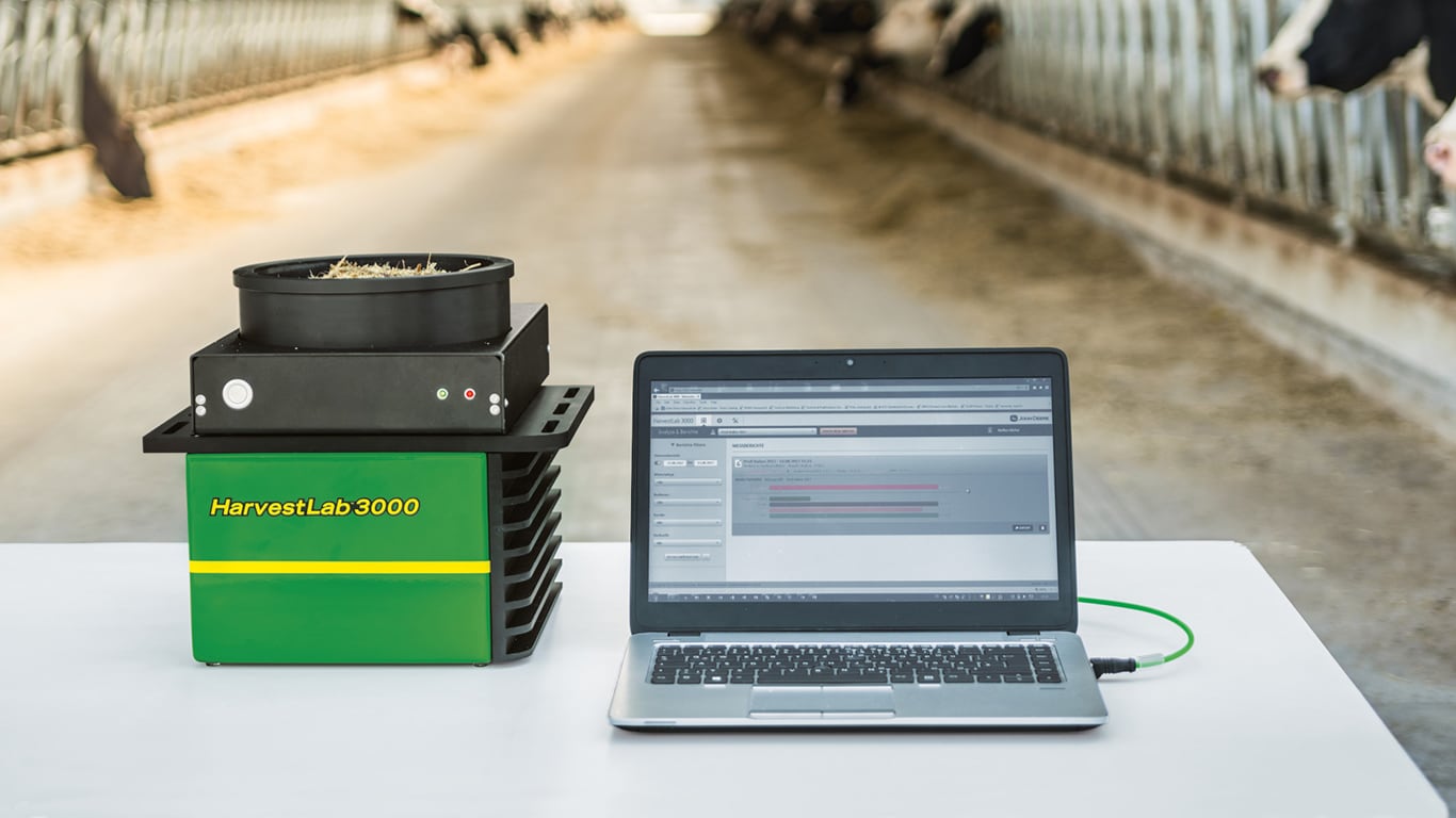 harvest lab sensor next to a laptop in a barn full of dairy cows